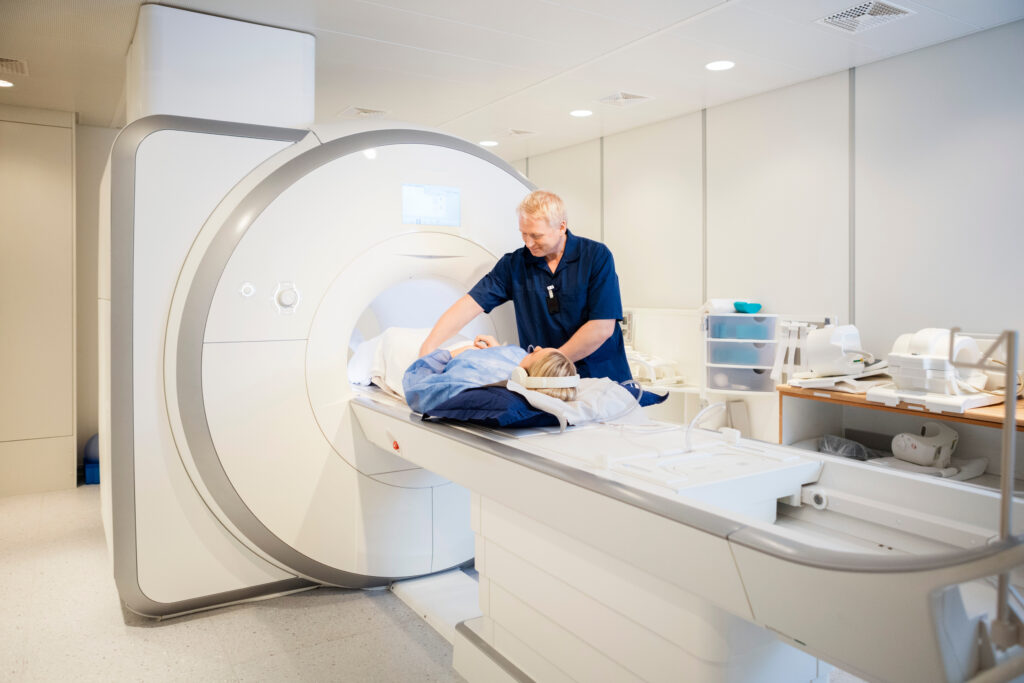Medical technician assisting a patient during MRI preparation inside a modern diagnostic imaging suite