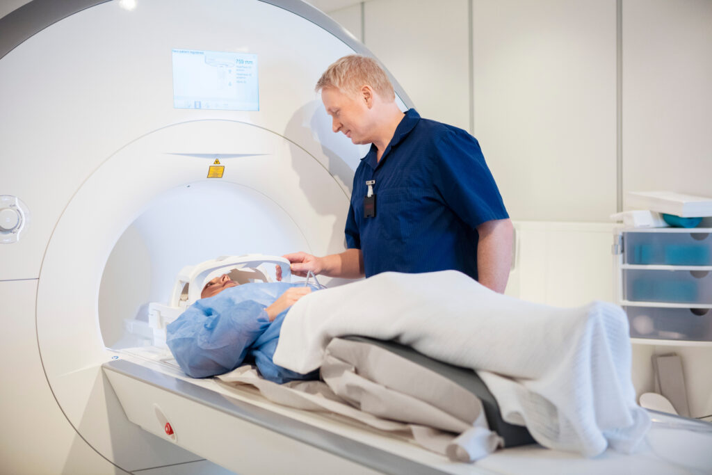 Medical technician assisting a patient positioned on an MRI scanner table during a diagnostic imaging exam