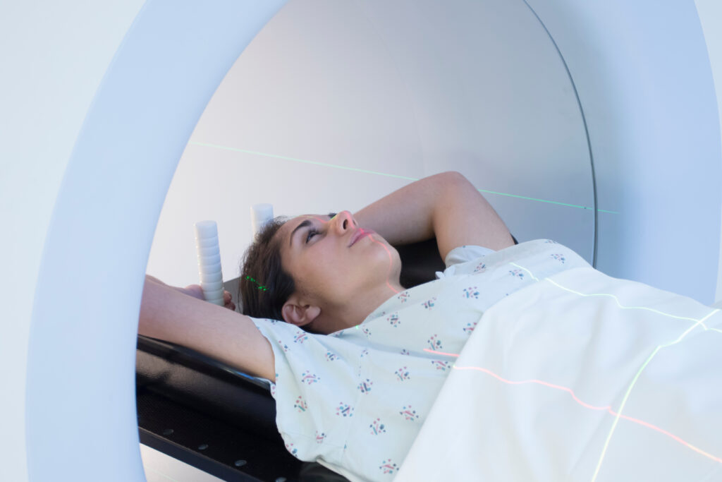 Patient lying on a CT scanner table with arms raised, preparing for a medical imaging scan