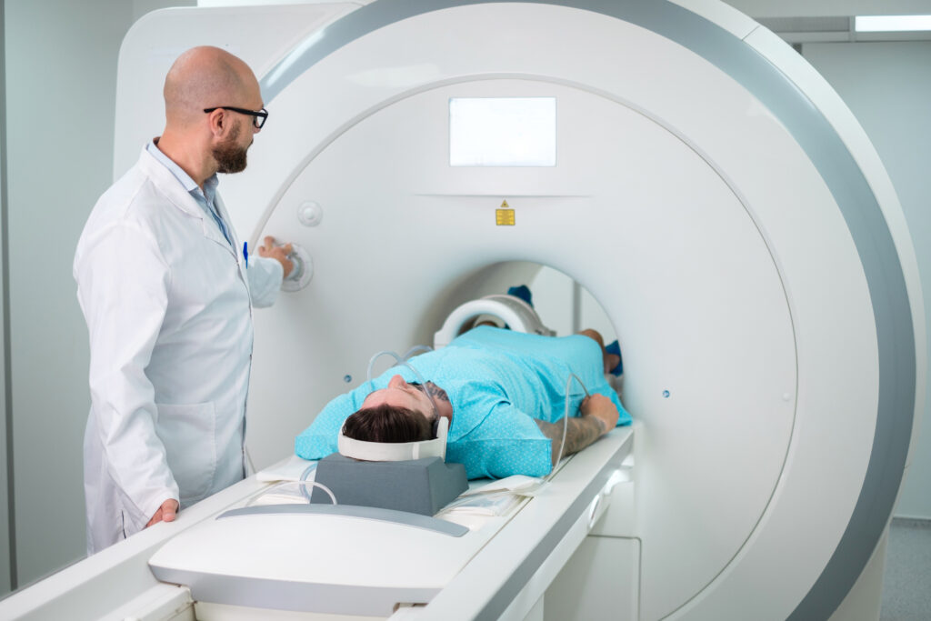 Patient lying on an MRI scanner table while a medical professional operates the imaging machine during an exam
