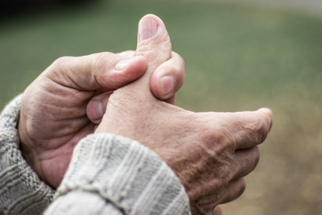 Close-up of hands gripping a thumb, indicating thumb joint pain or arthritis-related discomfort