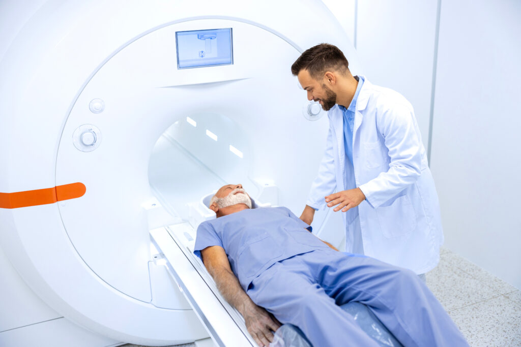 Patient lying on a CT scanner table while a medical technician assists during a diagnostic imaging procedure