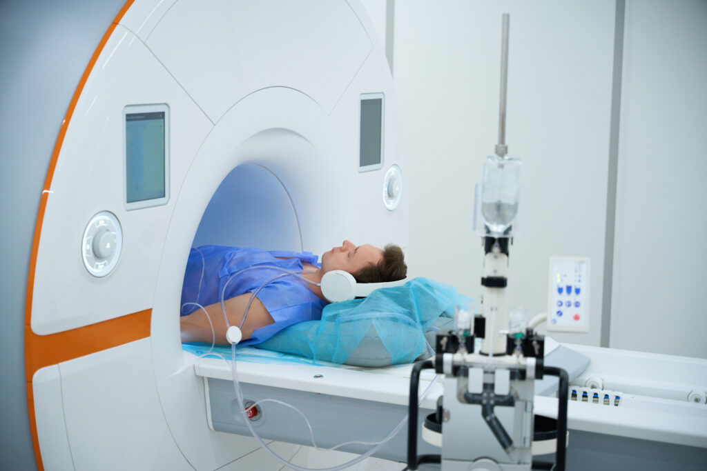 Patient wearing headphones while undergoing an MRI scan, lying still inside a diagnostic imaging machine